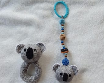 Puede incluir: Dos juguetes de koala de crochet gris. Un koala es un sonajero con un anillo y el otro koala está unido a una cadena de cuentas azules y marrones con un anillo de plástico azul.
