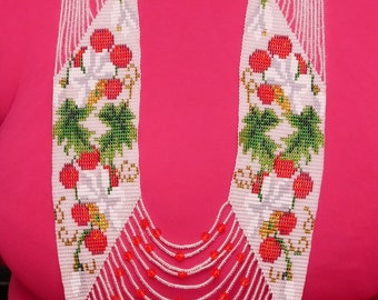 May include: A white beaded necklace with red and green accents. The necklace features a design of cherries and leaves. The necklace is layered and has a cascading effect.