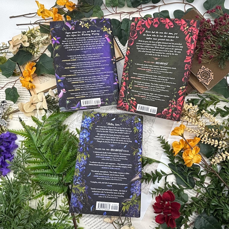 May include: Three hardcover books with floral designs and text, arranged with dried flowers and greenery. The book covers feature dark backgrounds with purple, red, and blue floral patterns. The text on the covers includes author names and book titles.