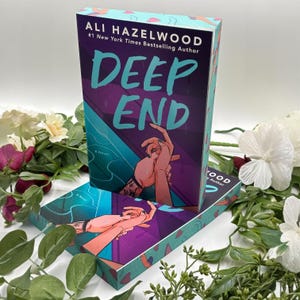 May include: A hardcover book titled "DEEP END" by Ali Hazelwood. The cover features a purple and teal design with the title in large teal letters and an illustration of hands. The book is a novel.