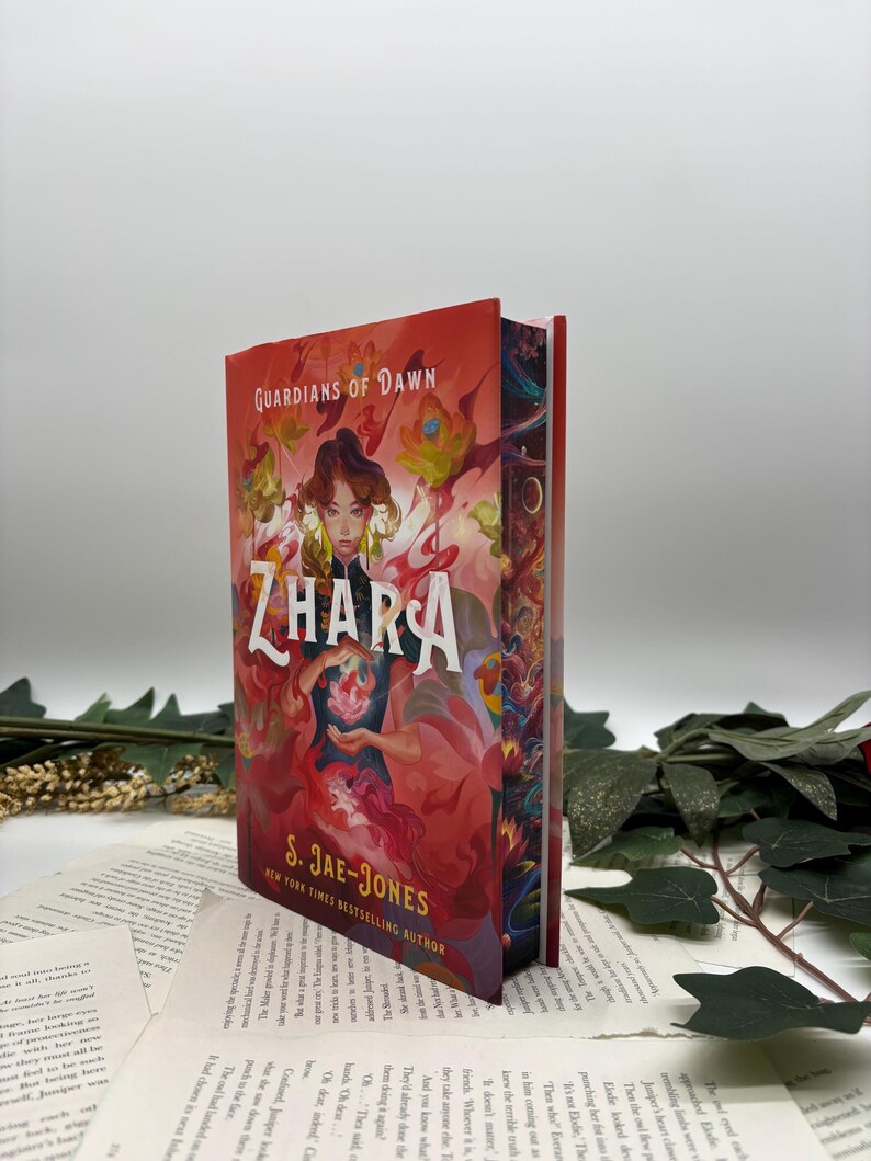 May include: A red, orange, and yellow fantasy book cover with a woman with long dark hair and a red dress holding a glowing flower. The title of the book is "ZHARA" and the author is "S. JAE-JONES".