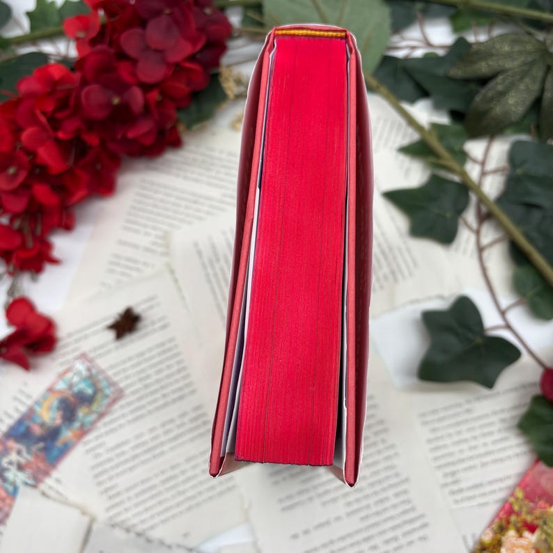 May include: The spine of a red hardcover book with a thin yellow line at the top.
