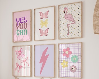May include: A set of six framed prints with a pink and purple color scheme. The prints feature a flamingo, butterflies, bows, a lightning bolt, and flowers with smiley faces. The prints are arranged in a grid on a white wall.