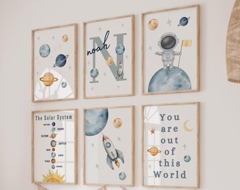 May include: A set of six space-themed prints for a nursery or child's room. The prints feature planets, stars, rockets, and an astronaut. The prints are in shades of blue, yellow, and white. The prints are framed in a simple wooden frame.