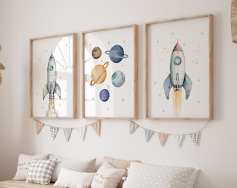 Puede incluir: Tres impresiones de acuarela enmarcadas con un tema espacial. Las impresiones presentan un cohete, planetas y estrellas. Las impresiones están colgadas en una pared blanca sobre un banco de madera con contenedores de almacenamiento.