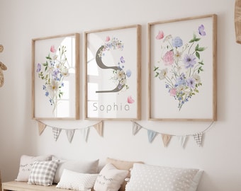 May include: Three framed prints with watercolor floral designs and the name "Sophia" on the middle print. The prints are hanging on a white wall above a wooden bench with pillows and storage bins.