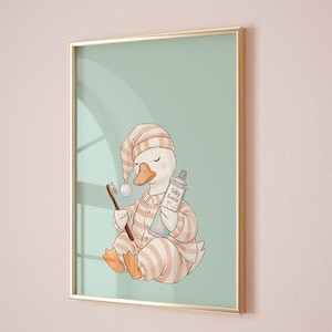 May include: Framed art print featuring a cartoon goose in striped pajamas and a nightcap, holding a toothbrush and toothpaste. The toothpaste tube reads "Silly Goose". The artwork has a soft color palette of beige, peach, and mint green, framed in gold.