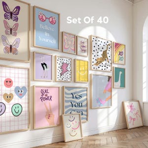 Op de afbeelding: Een verzameling van 13 ingelijste kunstprints met diverse ontwerpen, waaronder vlinders, smiley gezichten en inspirerende citaten. De prints zijn in verschillende kleuren, waaronder roze, blauw en geel. De tekst "Set Of 40" is zichtbaar.
