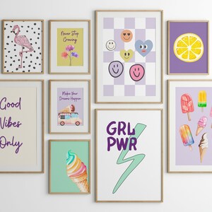 May include: A gallery wall of nine framed prints with various designs. The prints include a pink flamingo on a black and white polka dot background, a yellow background with flowers and the text "Never Stop Growing", a purple background with a checkered pattern and smiley faces, a purple background with a lemon slice, a cream background with the text "Good Vibes Only", a purple background with a ice cream truck and the text "Make Your Dreams Happen", a green background with a rainbow ice cream cone, a white background with the text "GRL PWR" and a green lightning bolt, and a purple background with various ice cream pops and cones.