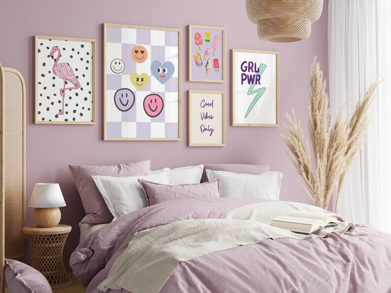 May include: A bedroom with a light purple wall and a bed with a light purple duvet and white pillows. There are several framed prints on the wall, including one with a flamingo, one with smiley faces, one with ice cream cones, and one with the text "GRL PWR" and a lightning bolt.