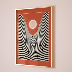 May include: Framed art print depicting a surreal landscape with black and white striped hills, silhouetted figures, and a full moon against a red-orange backdrop. The artwork is in a gold-coloured frame.