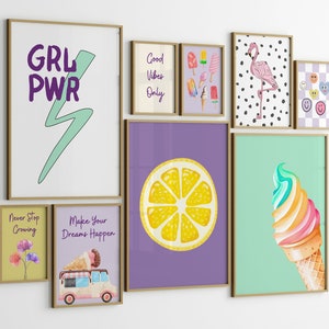 May include: A gallery wall of framed prints with various themes, including ice cream, lemons, flamingos, and motivational quotes. The prints are in a variety of colors and styles, and they are arranged in a grid pattern on a white wall.