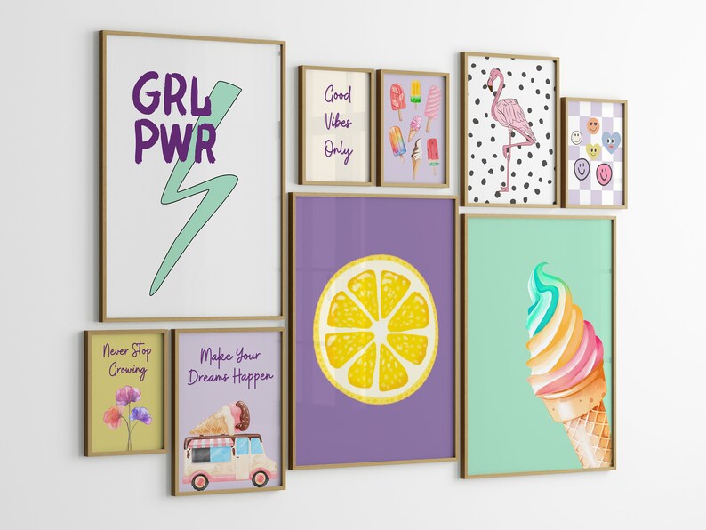 May include: A gallery wall of framed prints with various themes, including ice cream, lemons, flamingos, and motivational quotes. The prints are in a variety of colors and styles, and they are arranged in a grid pattern on a white wall.