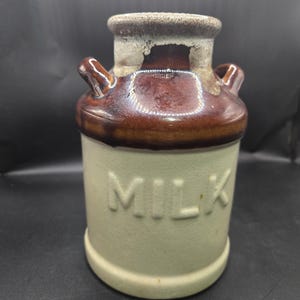 May include: A white ceramic mug with a black handle and the text "But First, Coffee" in a black, bold font. The mug is sitting on a wooden surface. The mug is approximately 4 inches tall.