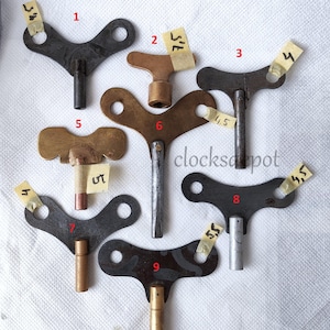 May include: Nine antique clock winding keys with different shapes and sizes. The keys are made of metal and have a variety of finishes, including brass, silver, and black. Some of the keys have numbers written on them.