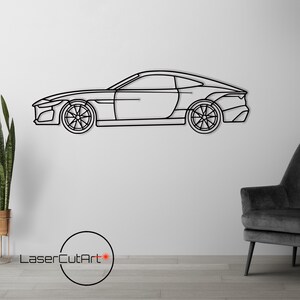 Puede incluir: Arte mural de metal negro de un coche deportivo. El perfil lateral del coche muestra ruedas detalladas. La obra de arte está montada en una pared blanca. El logotipo "LaserCutArt" está en la esquina inferior izquierda.