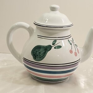 May include: White ceramic teapot with a lid, decorated with a green pear, pink cherries, and blue and pink stripes.