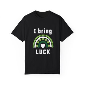 May include: Black t-shirt with a white graphic of a rainbow with shamrocks and a heart. The text "I bring luck" is below the rainbow.