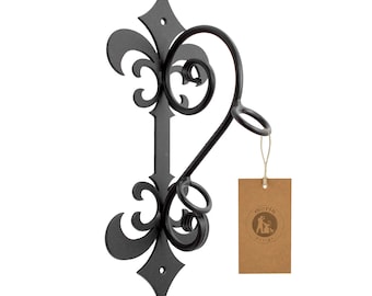 May include: Black metal wall mount with a decorative scroll design. It has two hooks for hanging items. The wall mount is labeled "moria crafts".