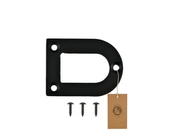 May include: Black metal D-ring with three screws and a brown tag. The D-ring has three holes for mounting and a rounded shape. The tag has a logo and the text "moria design".