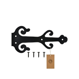 Puede incluir: Bisagra de metal negro con un diseño decorativo de desplazamiento. La bisagra está unida a un fondo blanco e incluye cuatro tornillos negros.
