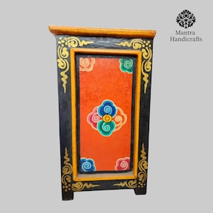 May include: A small, black wooden cabinet with a red, orange, blue, and green painted design. The cabinet has a yellow trim and gold accents.
