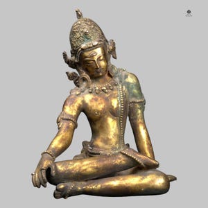 May include: A detailed bronze statue of a seated figure with ornate headdress and jewelry. The figure is in a meditative pose, with one hand resting on the knee. The statue has a weathered, antique appearance with shades of gold and green.