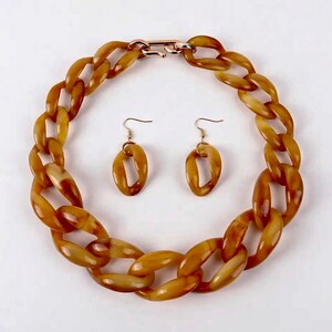 May include: A chunky brown resin chain necklace and matching earrings. The necklace has a gold clasp.