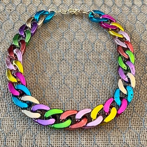May include: A colorful chain necklace with alternating links of blue, green, yellow, pink, red, and white.