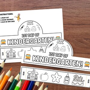 May include: A black and white printable paper crown with the text "1st Day of Kindergarten!" and school-themed illustrations. Includes instructions: Print out, color/decorate, and glue or tape ends. Colored pencils are in the foreground.