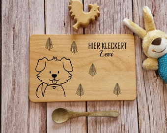 May include: A wooden plate with a cute dog illustration and the text "HIER KLECKERT Levi" engraved on it. The plate is surrounded by small tree illustrations.