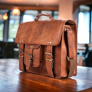 May include: A brown leather satchel with a top handle, shoulder strap, and multiple buckle closures. The bag has a flap closure and two front pockets. The leather has a distressed appearance with visible grain and variations in color. The hardware is brass-colored.