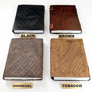 May include: Four leather-bound journals in black, brown, charcoal, and tobacco colours. Each journal has a unique embossed pattern on the cover. The text labels below each journal read "BLACK", "BROWN", "CHARCOAL", and "TOBACCO".