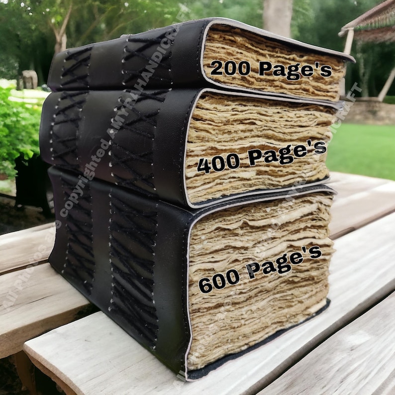 Puede incluir: Diarios apilados de cuero negro con detalles cosidos. Los diarios tienen p&aacute;ginas envejecidas de color crema. El texto en los diarios dice: "200 Page's", "400 Page's" y "600 Page's".