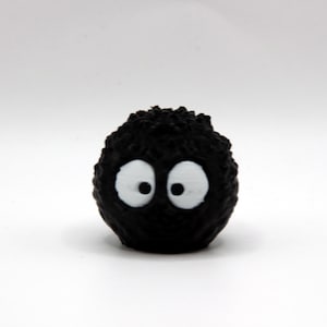 May include: A black fuzzy toy with two white eyes. The toy is round and has a textured surface.