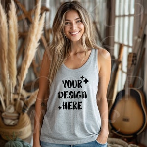 Puede incluir: Un top de tirantes gris con el texto "YOUR DESIGN HERE" en letras negras con estrellas a cada lado del texto.