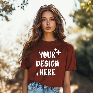 Könnte beinhalten: Ein rostfarbenes T-Shirt mit kurzen Ärmeln und einem Rundhalsausschnitt. Das Shirt hat den Text "YOUR DESIGN HERE" in Weiß auf der Vorderseite aufgedruckt.