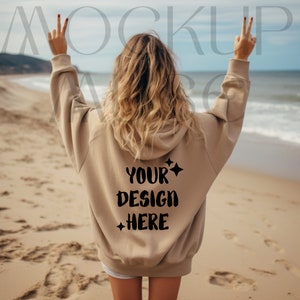May include: A tan hoodie with a black print that says "YOUR DESIGN HERE" on the back. The hoodie is being worn by a person on a beach.
