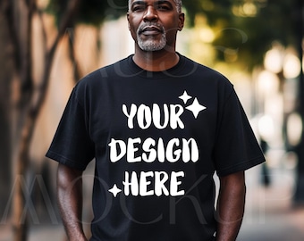 Puede incluir: Una camiseta negra con el texto "YOUR DESIGN HERE" en letras blancas. La camiseta la lleva puesta una persona con barba y pelo corto.