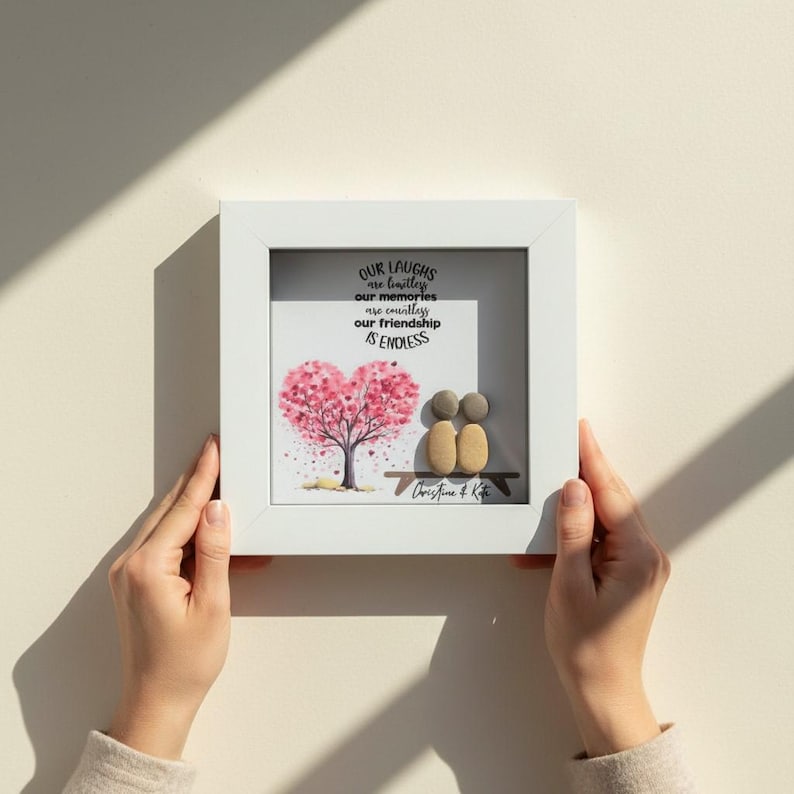 May include: A framed artwork with a white border. The artwork features a pink heart-shaped tree, two pebble figures, and the text "Our laughs are limitless, our memories are countless, our friendship is endless."