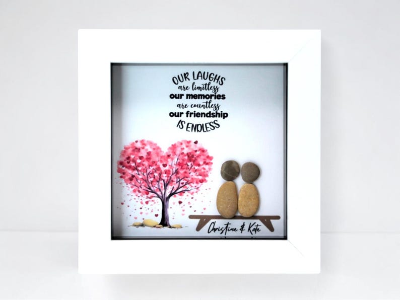 May include: A framed art piece with a white border. The artwork features a pink heart-shaped tree, two pebble figures on a bench, and the text "OUR LAUGHS are limitless, our memories are countless, our friendship IS ENDLESS".