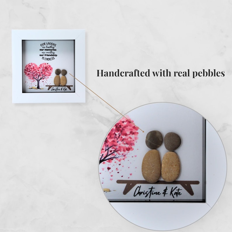 May include: A framed pebble art piece featuring two pebble figures on a bench beneath a pink tree. The artwork includes the text "Our laughs, our memories, our friendship is endless" and the names "Christine & Kate".