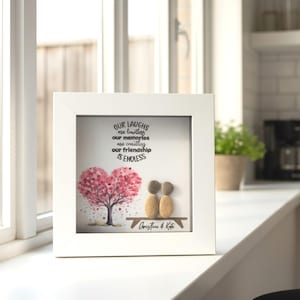 May include: A framed artwork with a white border. The artwork features a pink heart-shaped tree, two pebble figures, and the text "Our laughs are limitless, our memories are countless, our friendship is endless." The names "Christine & Kate" are at the bottom.