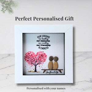 May include: White framed artwork with a heart-shaped tree in pink and red, two pebble figures, and the text "Our Laughs are Limitless, Our Memories are Countless, Our Friendship is Endless." Personalized with names.