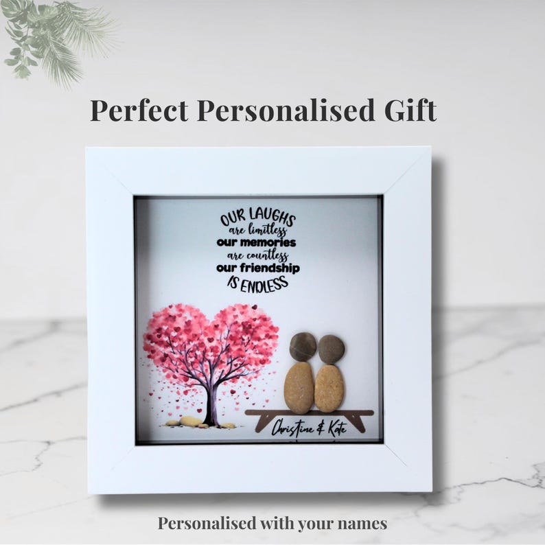 May include: White framed artwork with a heart-shaped tree in pink and red, two pebble figures, and the text "Our Laughs are Limitless, Our Memories are Countless, Our Friendship is Endless." Personalized with names.