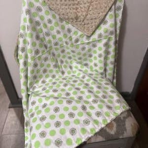 Puede incluir: Manta de beb&eacute; verde y blanca con un patr&oacute;n de lunares que presenta peque&ntilde;os c&iacute;rculos verdes con un contorno blanco. La manta est&aacute; hecha de tela suave y felpa y tiene un respaldo de vell&oacute;n beige.