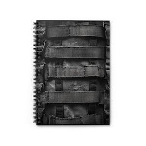 May include: Black and white image of a notebook with a black and gray camouflage pattern on the cover.