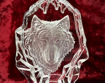 May include: A clear glass sculpture of a wolf's head, set against a background of frosted glass that resembles ice. The wolf's head is detailed and realistic, with a sharp, focused gaze.
