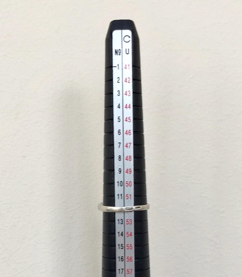 May include: A black ring sizer with white markings. The numbers on the sizer range from 41 to 57.