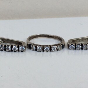 May include: A silver ring and a pair of earrings with clear cubic zirconia stones.